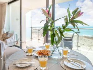 een tafel met een vaas met bloemen en glazen sinaasappelsap bij 2 Bed in Westward Ho 88853 in Westward Ho