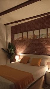 a bedroom with a large bed with a brick wall at La Sal Home Toledo in Toledo