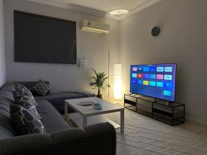 een woonkamer met een bank en een flatscreen-tv bij شقة فاخرة بدخول ذاتي/غرفة و صالة و مطبخ و حمام in Riyad
