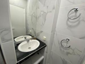 a white bathroom with a sink and a mirror at studio BORDEAUX CHARTRONS 2 in Bordeaux
