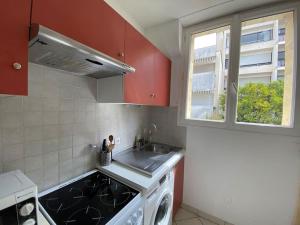 eine Küche mit roten Schränken, einem Waschbecken und einem Fenster in der Unterkunft studio BORDEAUX CHARTRONS 2 in Bordeaux