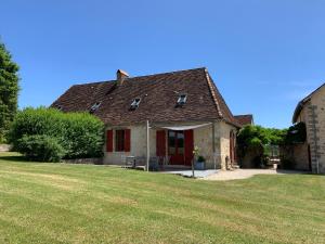 an old house with red doors and a grass yard at La Sautie in Bars