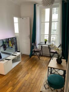 a living room with a television and a table at Joli petit 2 pièces in Asnières-sur-Seine