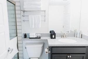 a white bathroom with a toilet and a sink at The Vinyl at Music Row - 1 Bedroom Apartment in Nashville