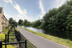 a river with a fence next to a road at Great location Modern refurbishment Free parking in Leeds