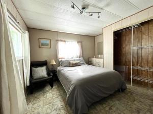 a bedroom with a large bed and a chair at Roberts Roost Resort in Quesnel
