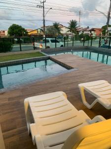 a pool with a bed and a bench next to it at Apartamento a Beira-Mar - Praia do Francês in Marechal Deodoro