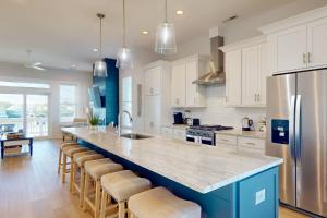 a kitchen with white cabinets and a blue island with bar stools at Blue Oasis in Carolina Beach