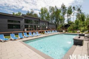 a swimming pool with lounge chairs and a house at Archibald - Cozy avec spa, sauna, piscine in Pont-Rouge