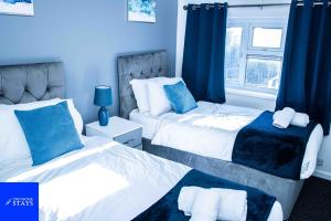 1 dormitorio con 2 camas y cortinas azules en 2ndHomeStays-Walsall- A Charming 3-Bed Home with Landscape View - Suitable for Contractors and Families -Large Parking for 3 Vans - Sleeps 8 - 7 mins to J10 M6 and 21 mins to Birmingham, en Bloxwich