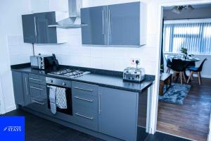 a kitchen with blue cabinets and a stove top oven at 2ndHomeStays-Walsall- A Charming 3-Bed Home with Landscape View - Suitable for Contractors and Families -Large Parking for 3 Vans - Sleeps 8 - 7 mins to J10 M6 and 21 mins to Birmingham in Bloxwich