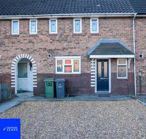 2ndHomeStays-Walsall- A Charming 3-Bed Home with Landscape View - Suitable for Contractors and Families -Large Parking for 3 Vans - Sleeps 8 - 7 mins to J10 M6 and 21 mins to Birmingham في Bloxwich: بيت من الطوب وامامه سلة مهملات