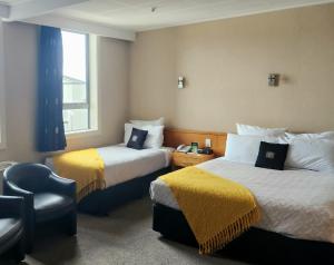 um quarto de hotel com duas camas e uma cadeira em Kelvin Hotel em Invercargill