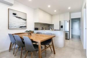cocina con mesa de comedor de madera y sillas en Elegant 2-Bed Apartment with Stunning Views, en Batemans Bay