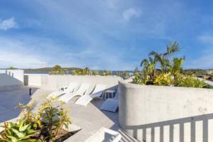 una fila de bancos blancos en un patio con vistas a la playa en Elegant 2-Bed Apartment with Stunning Views, en Batemans Bay
