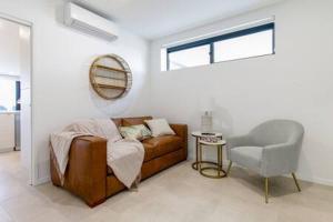 sala de estar con sofá y silla en Elegant 2-Bed Apartment with Stunning Views, en Batemans Bay
