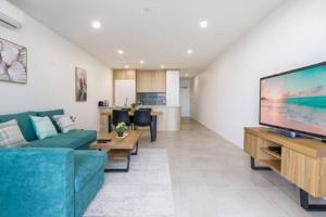 een woonkamer met een blauwe bank en een flatscreen-tv bij Stunning 1-Bed Bayside Apartment with Superb Views in Batemans Bay