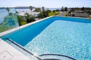 een groot blauw zwembad met uitzicht op de oceaan bij Stunning 1-Bed Bayside Apartment with Superb Views in Batemans Bay