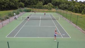 three people playing tennis on a tennis court at La Sautie in Bars