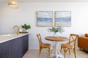 a kitchen and a table and chairs in a kitchen at Elegant Bay Side 1-Bed Apartment with Views in Batemans Bay