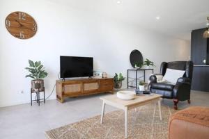 een woonkamer met een tv en een bank en een tafel bij Elegant Bay Side 1-Bed Apartment with Views in Batemans Bay