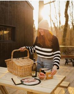 a woman standing next to a picnic table with a basket at La tiny house de la Blandinière in Vertou