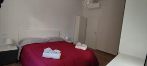 1 dormitorio con 1 cama roja y 2 toallas en BOLOESTHOUSE, en Bolonia