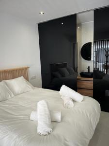 Un dormitorio con una cama blanca con toallas. en Suite PLAYAMAR con jacuzzi, en Torremolinos