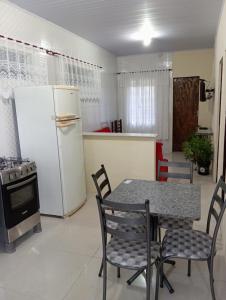 a kitchen with a table and a white refrigerator at Flor da serra in Santo Antônio do Pinhal