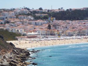 a group of people on a beach near the ocean at Holidays 71 in Nazaré