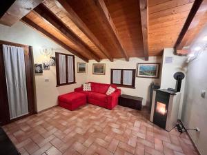 sala de estar con sofá rojo y chimenea en Casa Rilassa Monte, en Cividale del Friuli