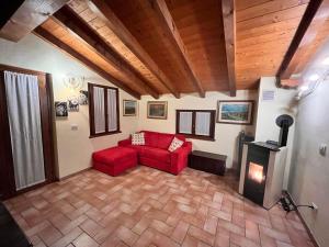 a living room with a red couch and a fireplace at Casa Rilassa Monte in Cividale del Friuli