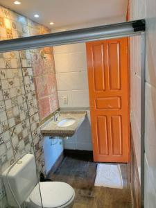 uma casa de banho com um WC, um lavatório e uma porta laranja em Casa Tío Luiz em Aquiraz