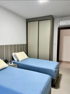 two beds in a room with blue beds in it at Casa ilha Itaparica in Armação do Tairu