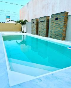 a swimming pool with blue water in front of a building at Casa ilha Itaparica in Armação do Tairu