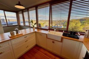 a kitchen with a counter with a sink and windows at Renovated Cottage Near Cataract Gorge Launceston in Royal Park