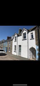 a large white house with a car parked in front of it at 4 bedroom townhouse Kirkcudbright in Kirkcudbright