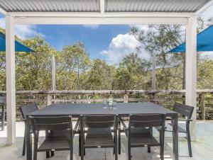 a dining table and chairs on a patio with blue umbrellas at Hastings Cove Holiday Apartments in Hastings Point