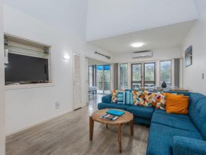 a living room with a blue couch and a table at Hastings Cove Holiday Apartments in Hastings Point