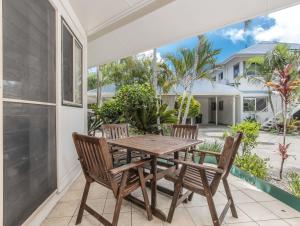 een houten tafel en 2 stoelen op een patio bij Hastings Cove Holiday Apartments in Hastings Point