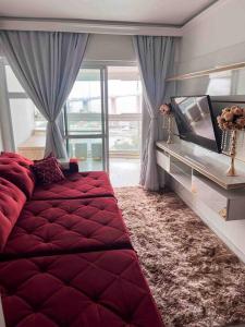 a bedroom with a red bed and a television at Apartamento com vista para o mar in Vitória