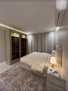 um quarto com uma cama e uma mesa com um candeeiro em شقق سمارت انترى بالملقا em Riyadh