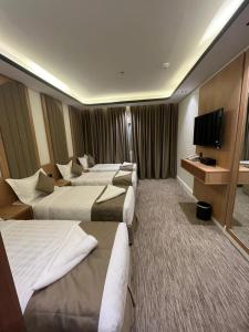 a hotel room with three beds and a flat screen tv at فندق سما المقام in Jarwal