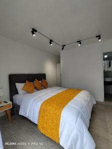 um quarto com uma grande cama branca com cobertor amarelo em Centro Vacacional "El Pro" em Puerto López