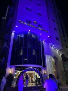 a group of people standing outside of a building with purple lighting at فندق سما المقام in Jarwal