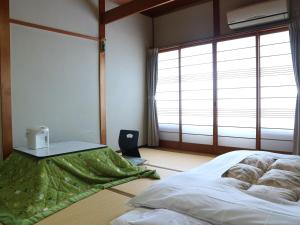 a bedroom with a bed and a table and windows at Kanko Ryokan Yamato in Ikuma +33 photos
