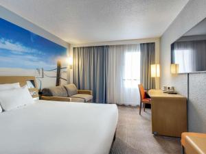 a hotel room with a large bed and a desk at Novotel Paris Est in Bagnolet