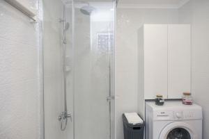 a bathroom with a shower and a washing machine at Beach Glove Ericeira II in Ericeira