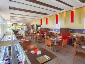 a restaurant with wooden tables and chairs and red flags at ibis Medellin in Medellín