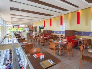 un restaurant avec des tables et des chaises en bois et des drapeaux rouges dans l'établissement ibis Medellin, à Medellín